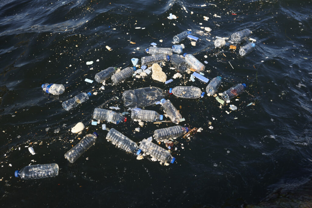 Plastic bottles and debris floating in polluted seawater, highlighting the environmental impact of plastic waste on marine ecosystems.